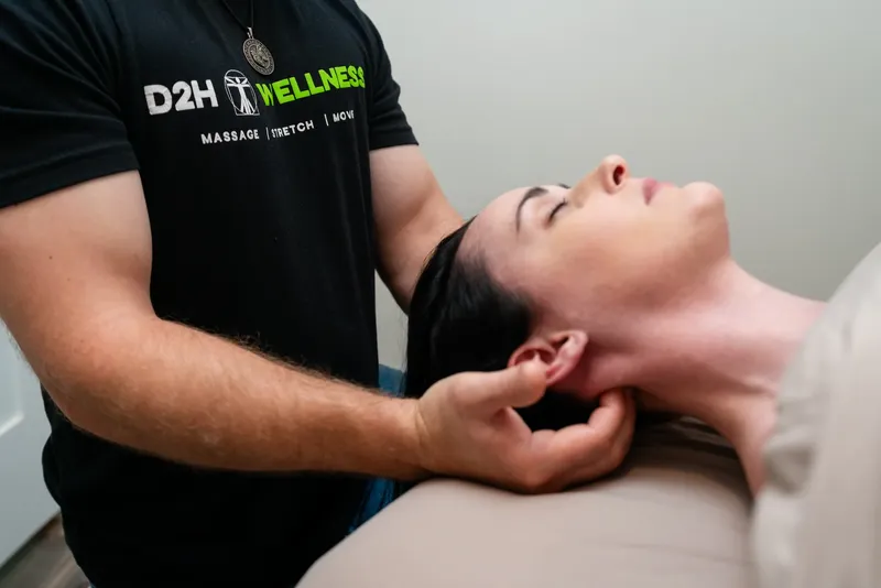 Therapist gently supporting a client's head and neck at D2H Wellness